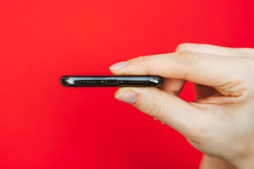 Holding a new smartphone, isolated on red background