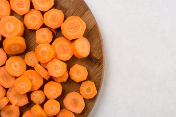 Chopped carrot on the wooden board with copy space above white marble