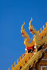 Fototapeta na wymiar A detail of northern thai temple roof ,Naga , under clear blue sky