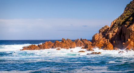 Shoreline of Phillip Island in Victoria Australia. Ocean waves breaking on the brown rocks of cape...