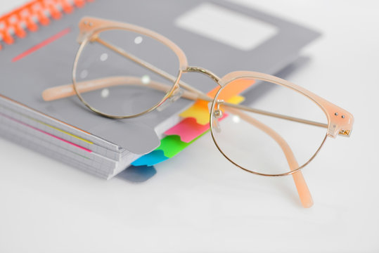 Eye glasses with spiral notebook on white background