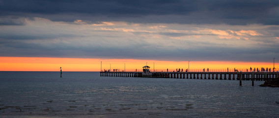 Mordialloc pier near Melbourne Australia at sunset with golden sky and clouds .