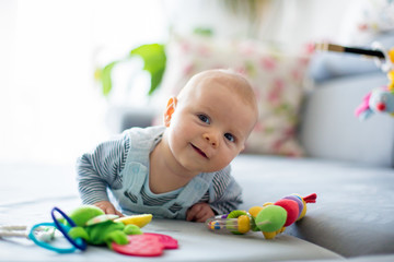 Cute baby boy, playing with toys in a sunny living room - obrazy, fototapety, plakaty