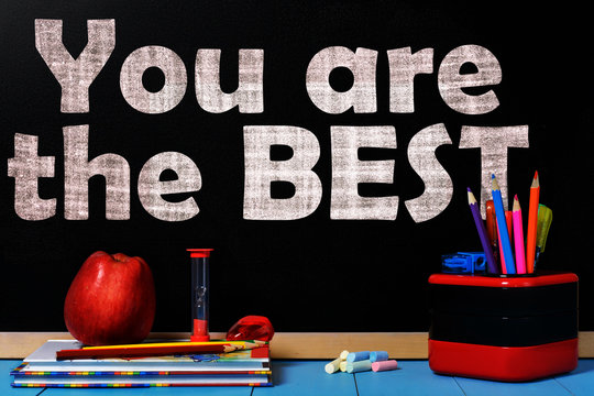 Text you are the best on black chalkboard with school accessories