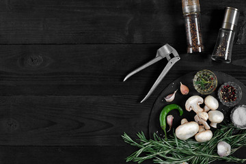 Fototapeta na wymiar Fresh mushrooms with spices and herbs on a black board.