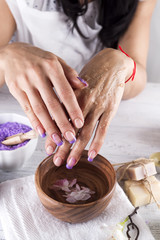 Young woman applies a coffee scrub on hands