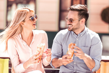 Young couple enjoying and eating sandwiches.