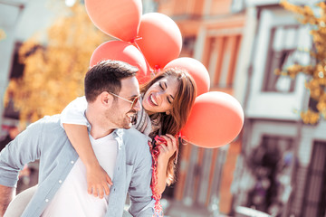 Happy couple in love enjoying sunny day with red ballons.