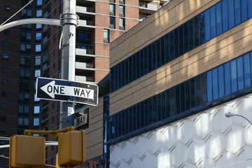 ONE WAY road sign points left on New York street