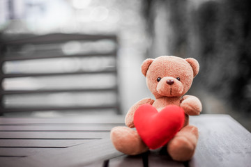 bear doll and red heart on the table with dramatic tone