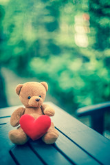 bear doll and red heart on the table with dramatic tone