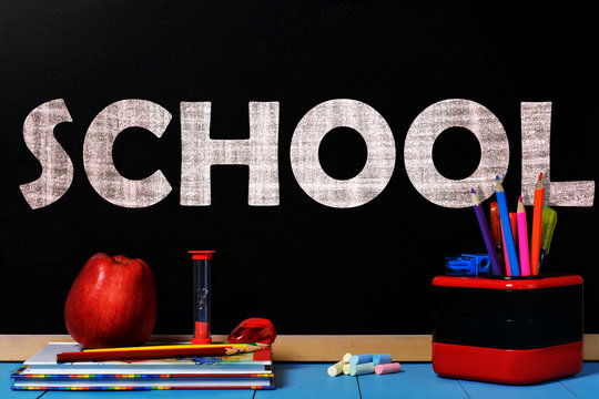 Text School on black chalkboard with school accessories