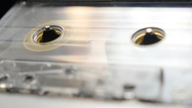 Plastic transparent cassette in casettophone footage - Close-up of supply spindle rotation shallow DOF