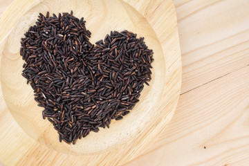 Close-up brown rice or riceberry organic food in bowl healthy on wood texture