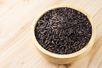 Close-up brown rice or riceberry organic food in bowl healthy on wood texture