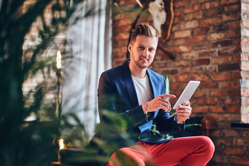 Obraz premium A man using tablet PC in a room with loft interior.