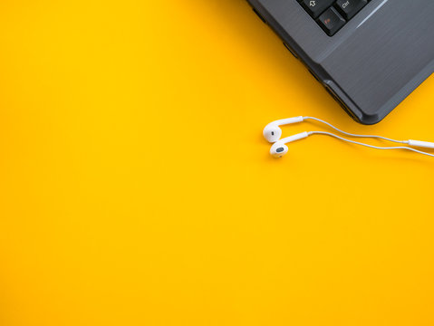 earphones with laptop on yellow background