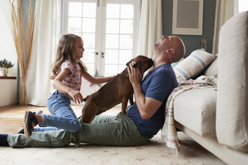 Father and daughter playing with their dog at home