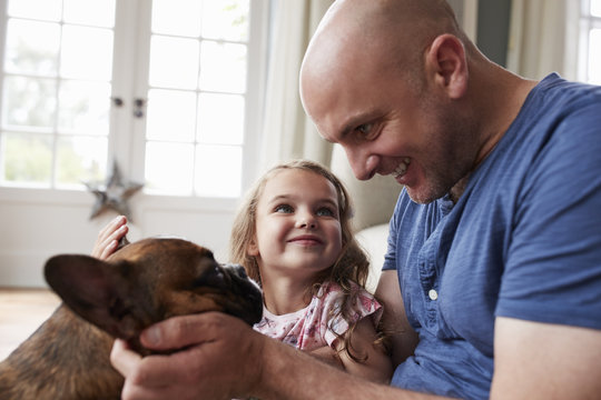 Father and daughter playing with their dog at home