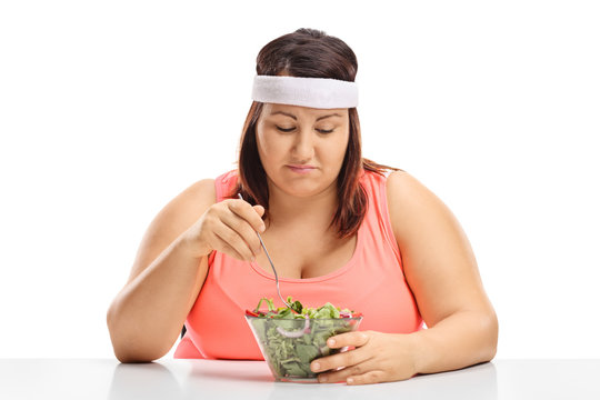 Sad Overweight Woman Sitting At A Table And Looking At A Bowl Of Salad