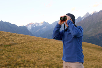 tourist with binoculars looking in a mountainous area in Georgia