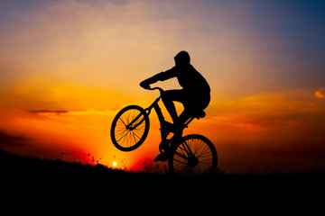 Fototapeta na wymiar Boy riding bicycle on background sunset.