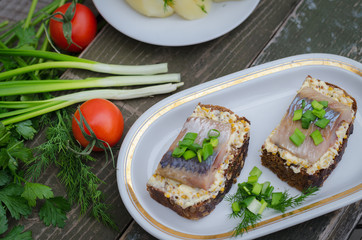 Herring, green onions, butter, French mustard and a slice of rye bread on an old wooden table.