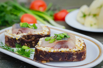 Herring, green onions, butter, French mustard and a slice of rye bread on an old wooden table.