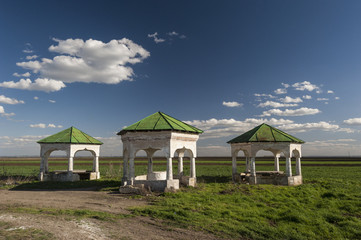 Fototapeta na wymiar Water wells in Romania/Countryside field with three water wells covered with oriental influenced architecture constructions in south Romania.