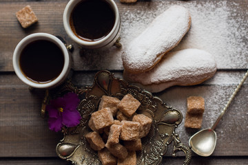 Cake eclair with coffee and cane sugar on a wooden background