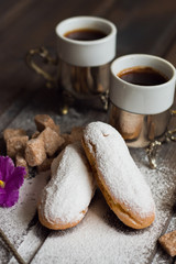 French eclairs with coffee on a wooden background