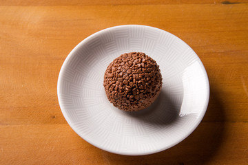 Traditional brazilian sweets - brigadeiros - over wood background.