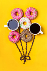 Balloon with donuts and cups of coffee on yellow background