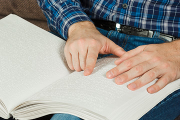 The blind man was reading a book written on Braille. Touch your finger on the braille code. A book with Braille text