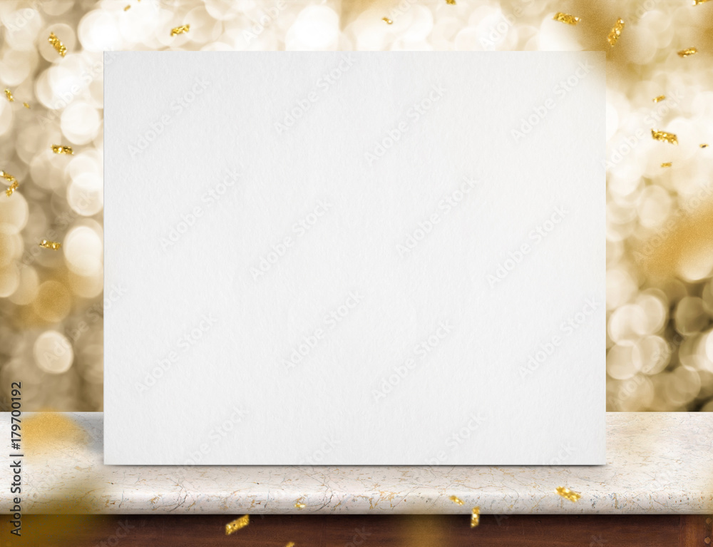 Poster blank white paper poster on marble table with gold sparkling confetti at gold bokeh lights at backgr