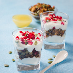 Honey pomegranate breakfast granola parfait on light blue background. Selective focus, space for text. 