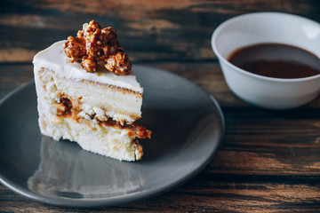 Slice of cheesecake topped with caramel popcorn on the wooden background. Artwork.
