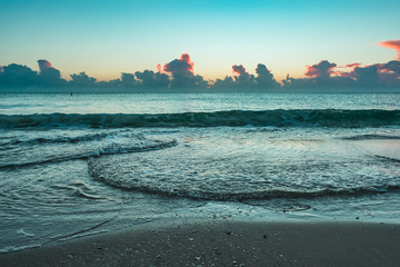 cool morning at the beach with the sun rising behind the clouds