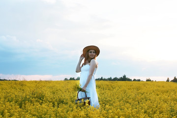 Girl in straw hat in a field of yellow flowers blossoming