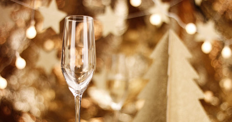 Sparkling wine in a flute glass on the background of stylish Christmas decorations in golden tones