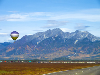A balloon flies over the village among the high mountains