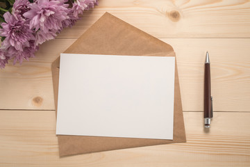 Envelope, pen and flowers on wooden background  	