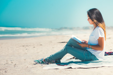 Young woman reading on sandy beach