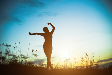 Silhouette of woman praying over beautiful sky background