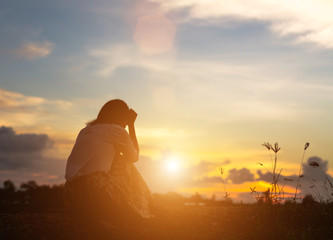 Silhouette of woman praying over beautiful sky background