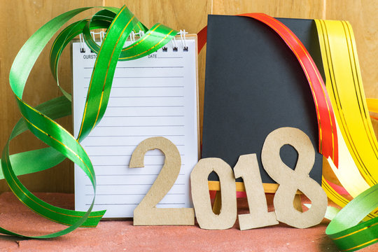 Notepad with number paper 2018 and ribbon on wood background. Using wallpaper or background. for happy new year image. And welcome new year photo.