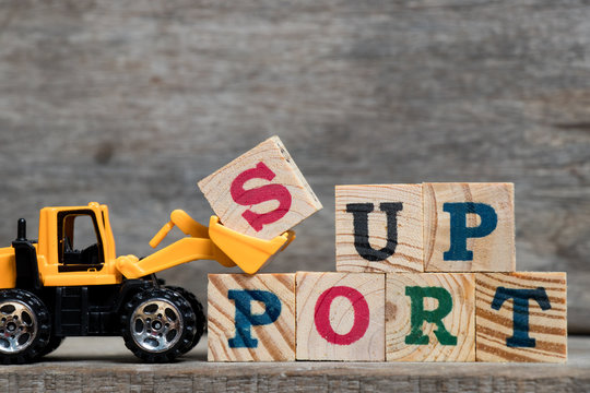 Yellow plastic bulldozer hold letter S to complete word support on wood background