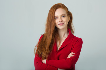 Obraz premium beautiful young smiling girl with red hair in a red sweater on a light background