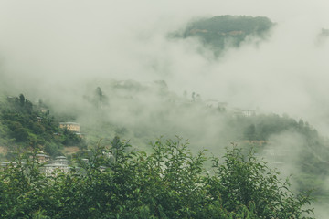 View of traditional Bhutanese buildings with foggy hills, Bumthang, Bhutan, Asia.