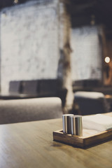 Salt and pepper bottles on wooden restaurant table